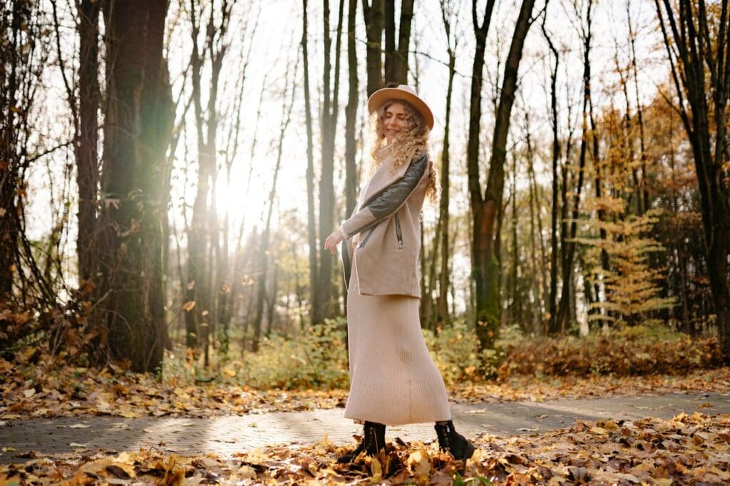 Woman posing outdoors in Friendsgiving outfit, sweater dress, boots, and hat