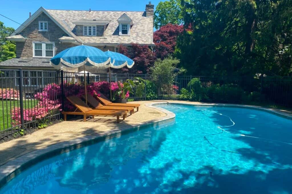 a pool outside a stone house with lounge chairs