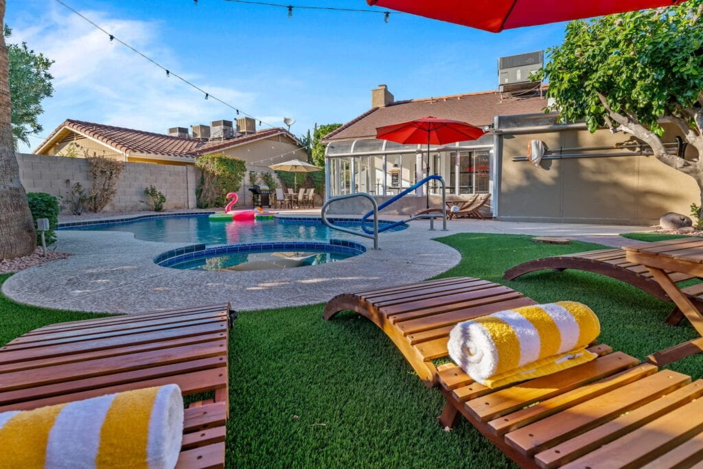 Phoenix-area backyard with pool, hot tub and wooden loungers with yellow and white striped towels