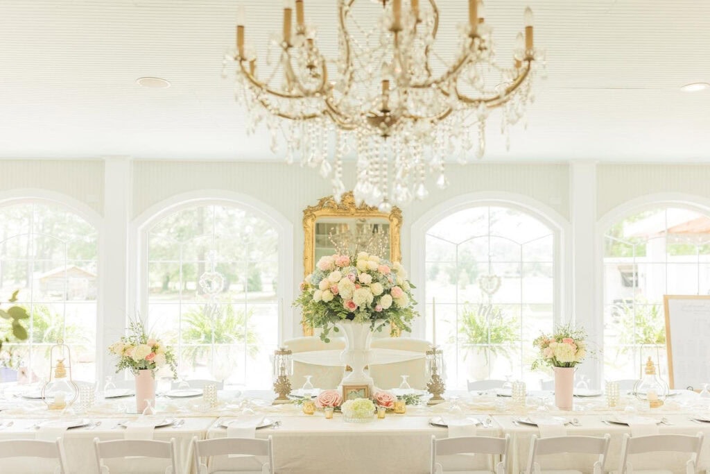 Formal dining space with large arched windows set up for a wedding reception with pink, blue and white flowers