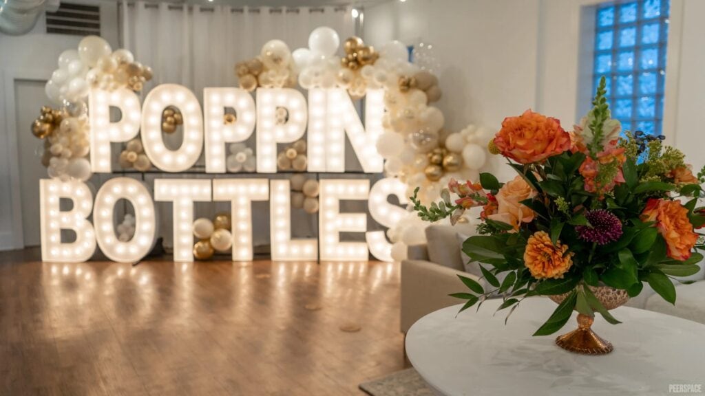 Beautiful bouquet sits on a table with a light-up Poppin' Bottles sign in the background