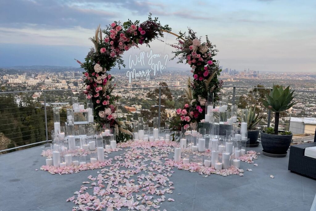 a rooftop proposal arch with candles and rose pedals