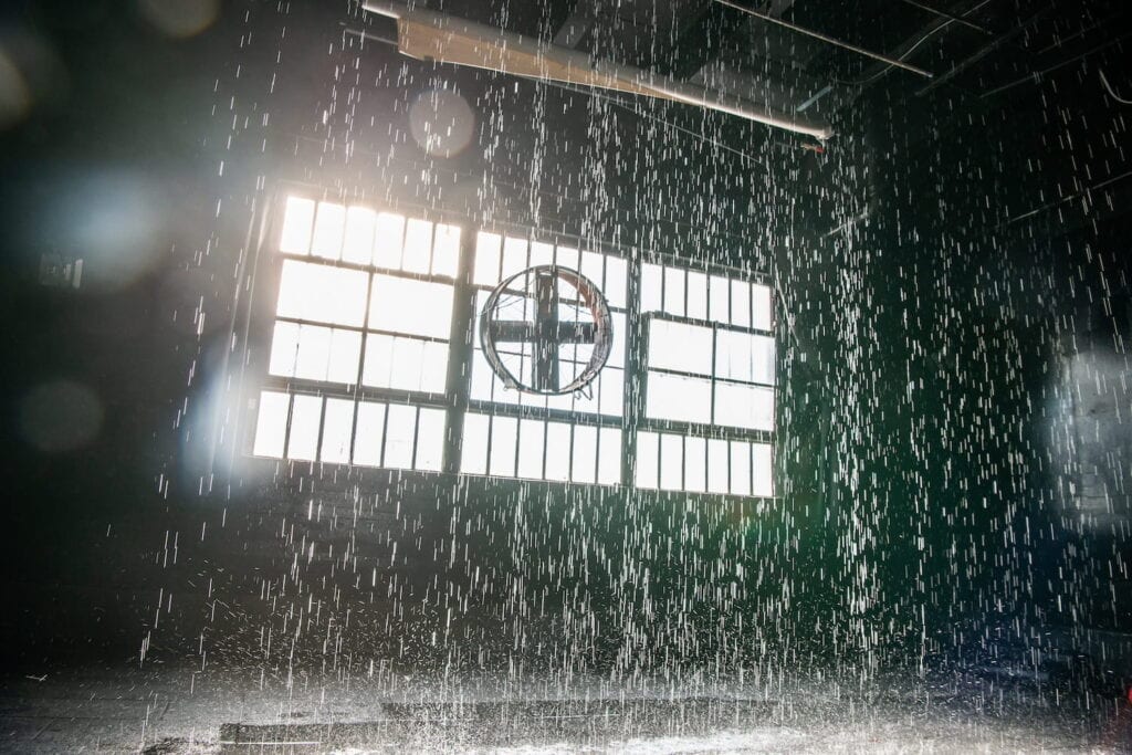 Los Angeles studio set up as a rain room by a large window with an industrial fan in the middle