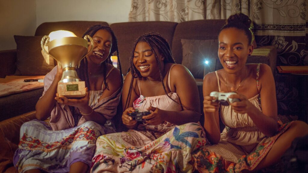 Three friends playing Galentines games with controllers and trophy