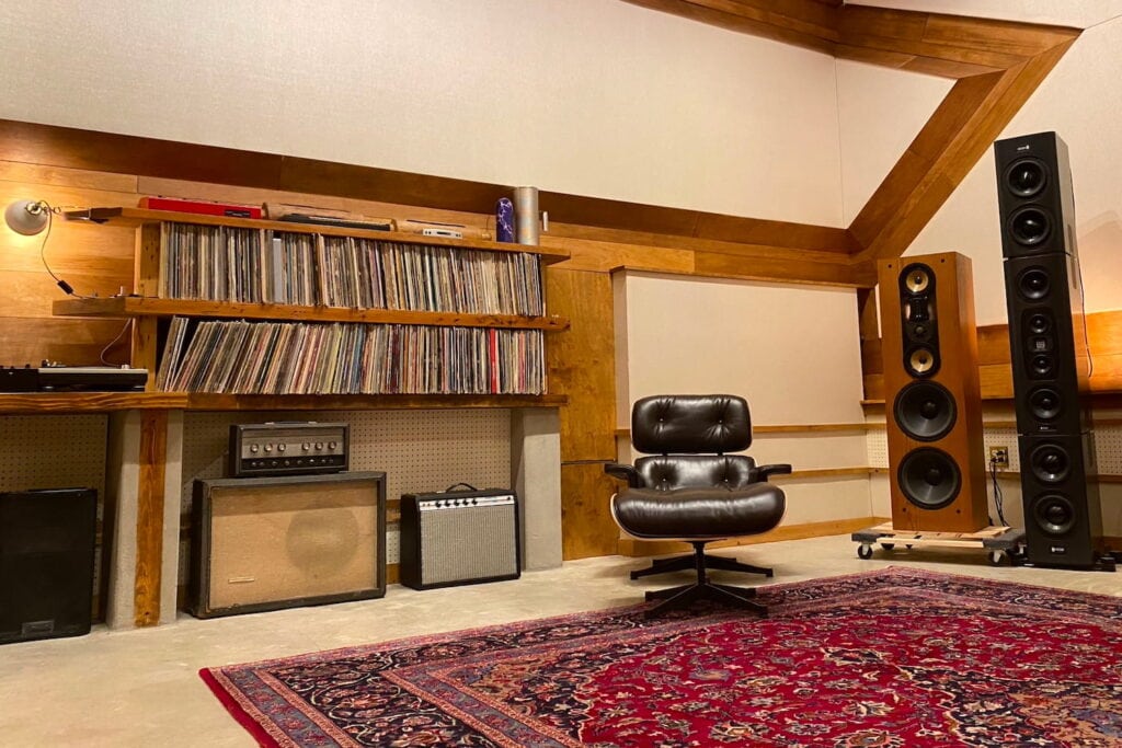 A music recording studio with large speakers and a wall full of records