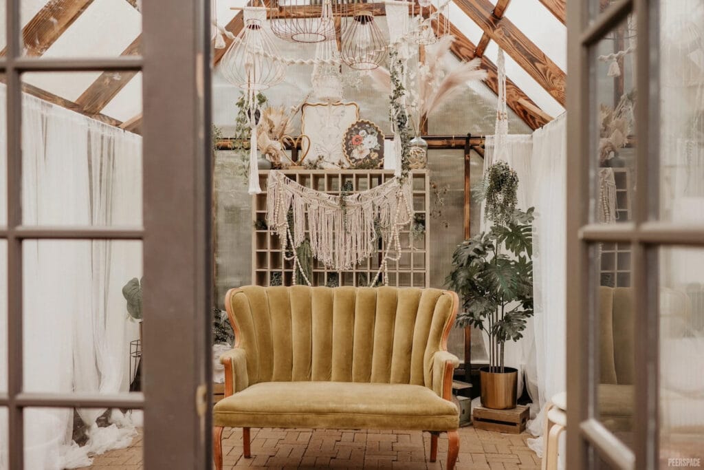 High-backed beige couch sits in femininely decorated glass studio