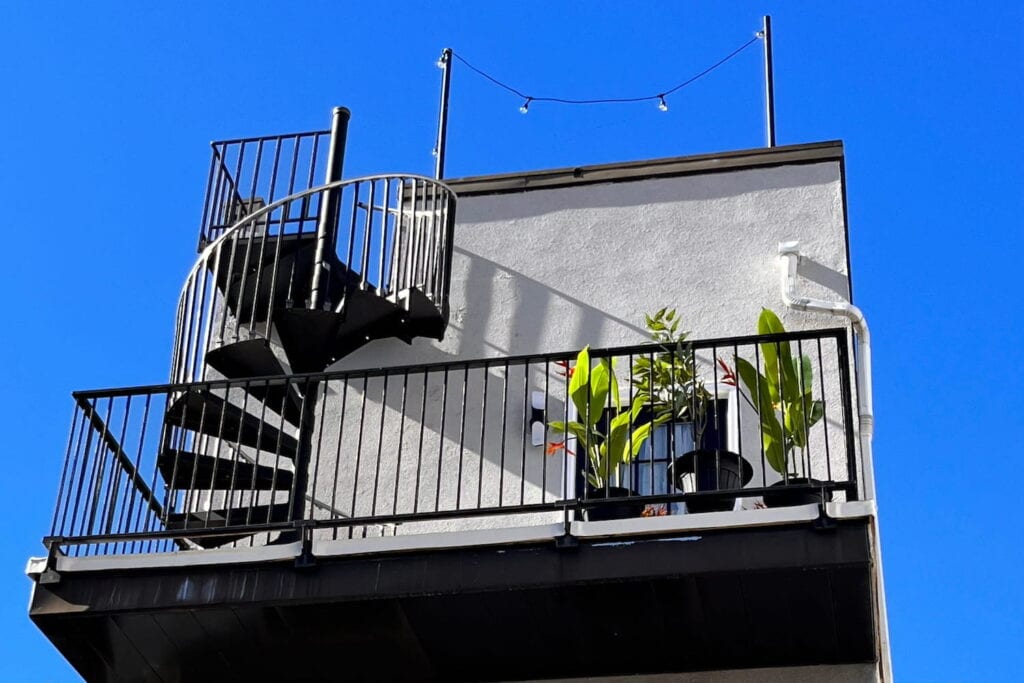 A spiral staircase leads to a roof deck on top of a row home.