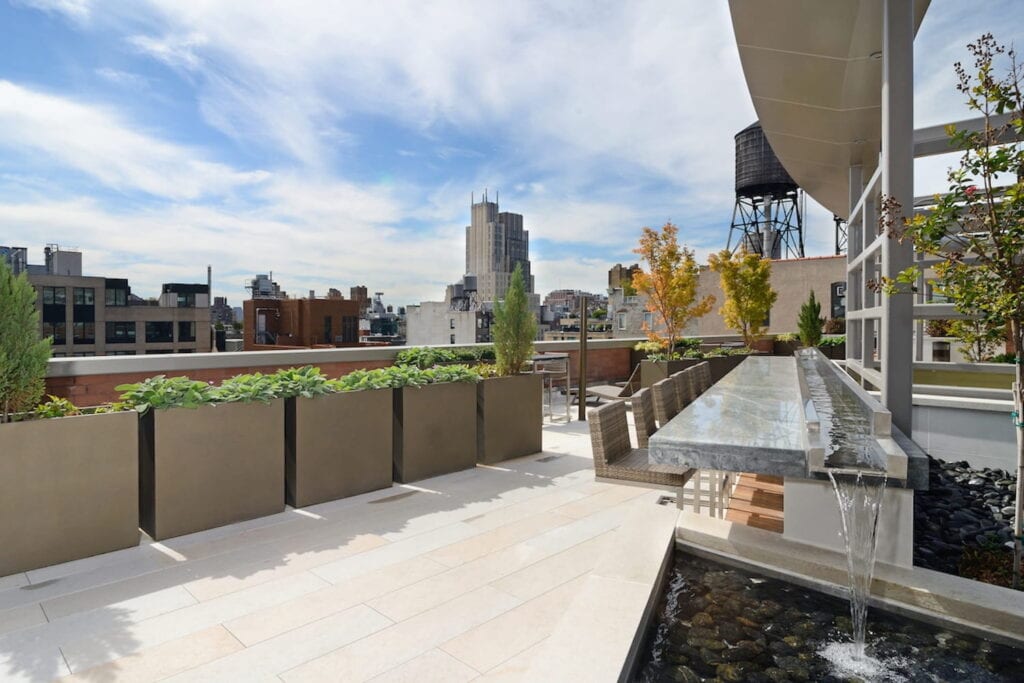 Planters and trees surround an open-air rooftop bar in New York City