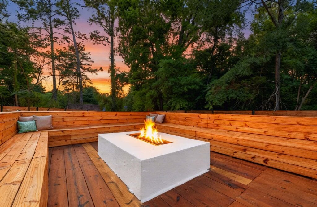 Deck area with fire pit in the woods with sun setting in the background
