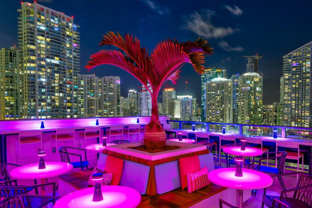 Neon lights illuminate a rooftop bar in Miami with city views