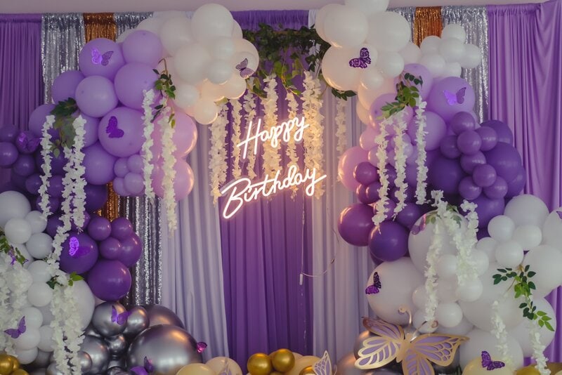 happy birthday neon sign lit up against a lavender background