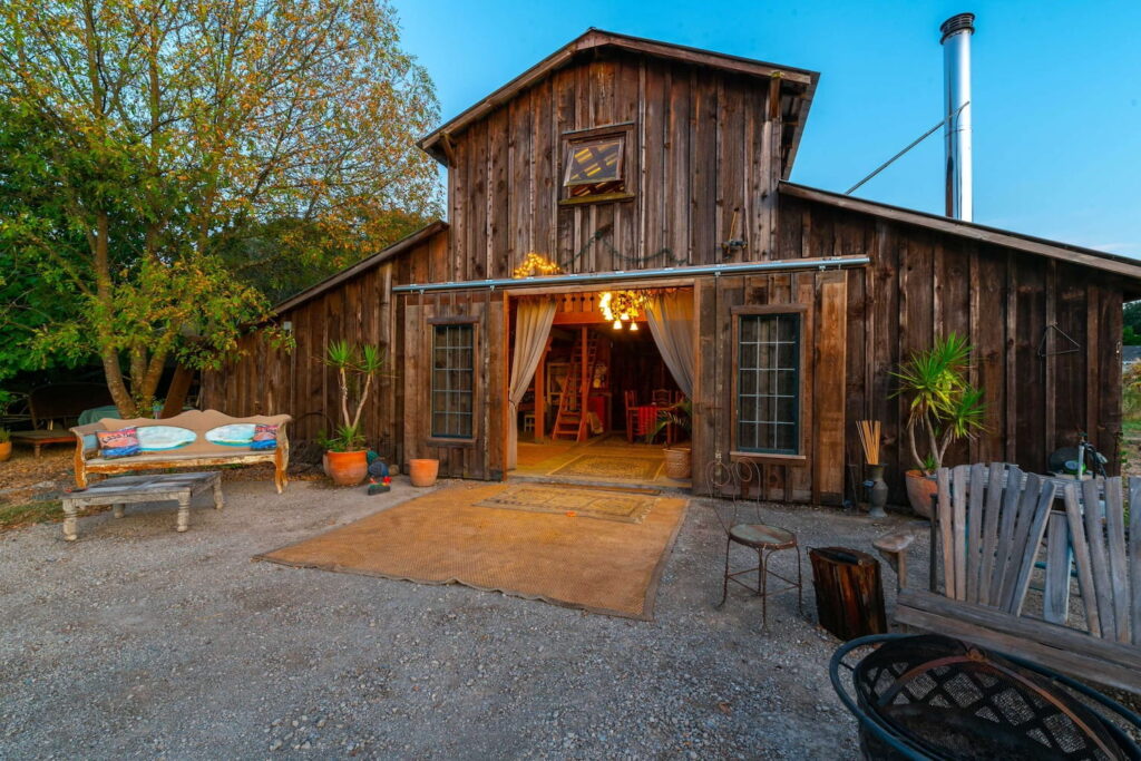 A rustic barn in opens to a dimly-lit event space surrounded by lush greenery