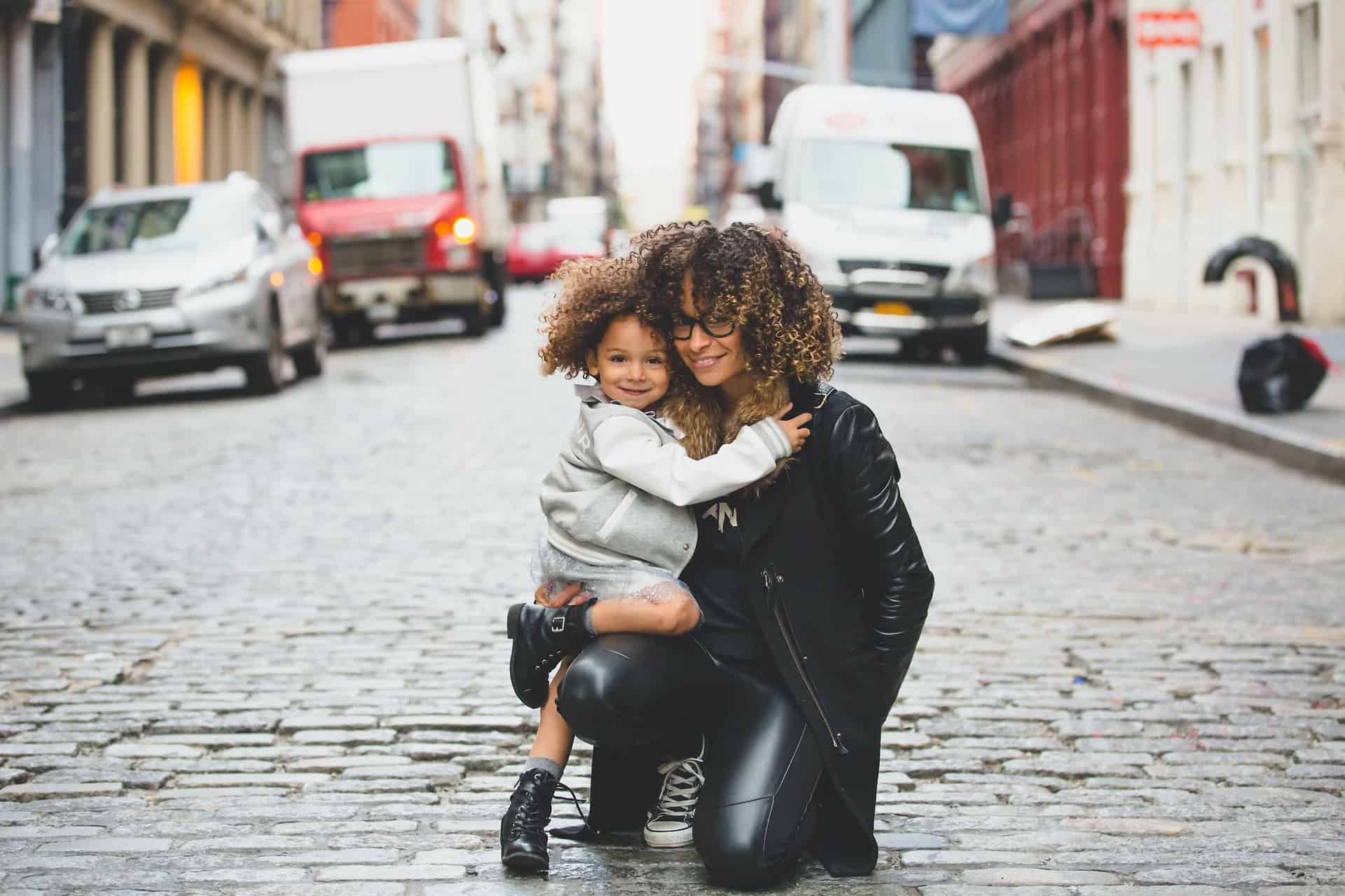 mother and daughter posing on cobblestone street
