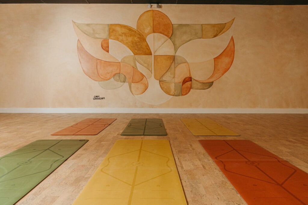 A serene bohemian yoga space with a dreamy mural on the wall and matching yoga mats on the floor