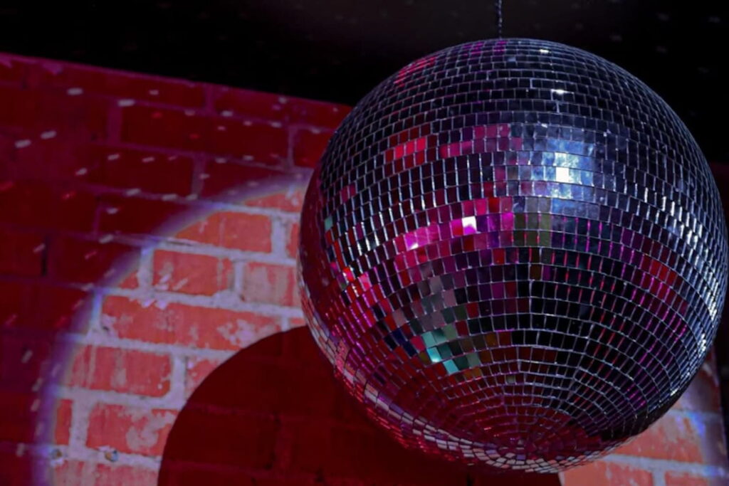 A disco ball hangs against a brick wall
