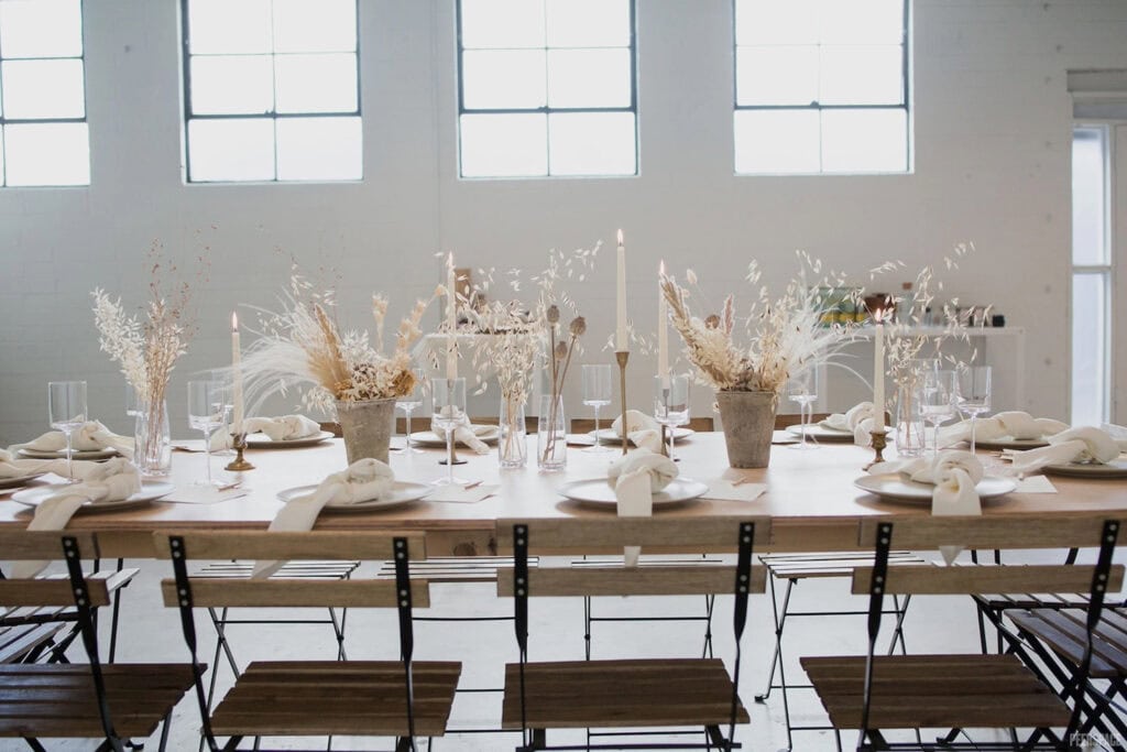 Natural elements decorate a simple table set for a small dinner party in a bright, airy space.