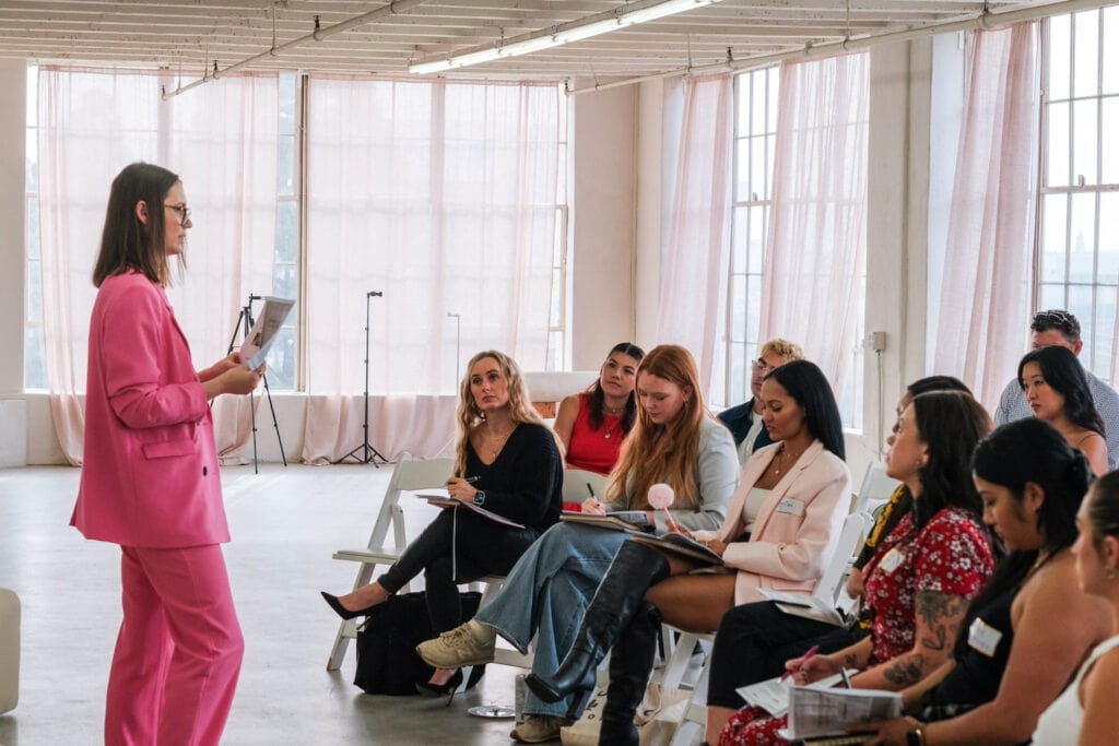 A speaker addresses a small group in a bright, open space