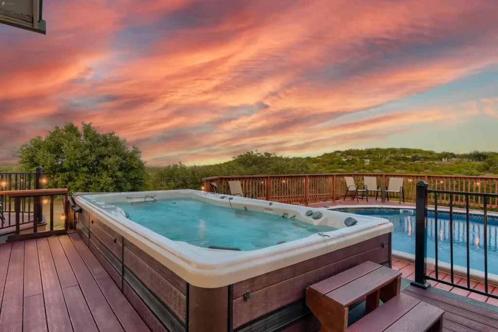 A big hot tub on a deck next to a swimming pool
