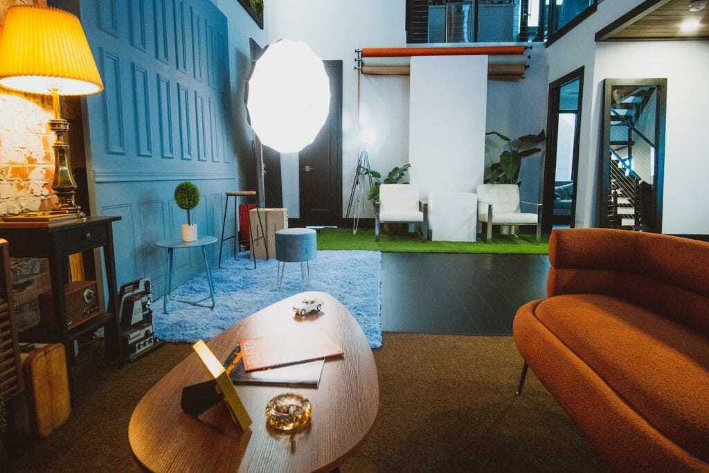 A studio space is outfitted with retro living room furniture and production lights