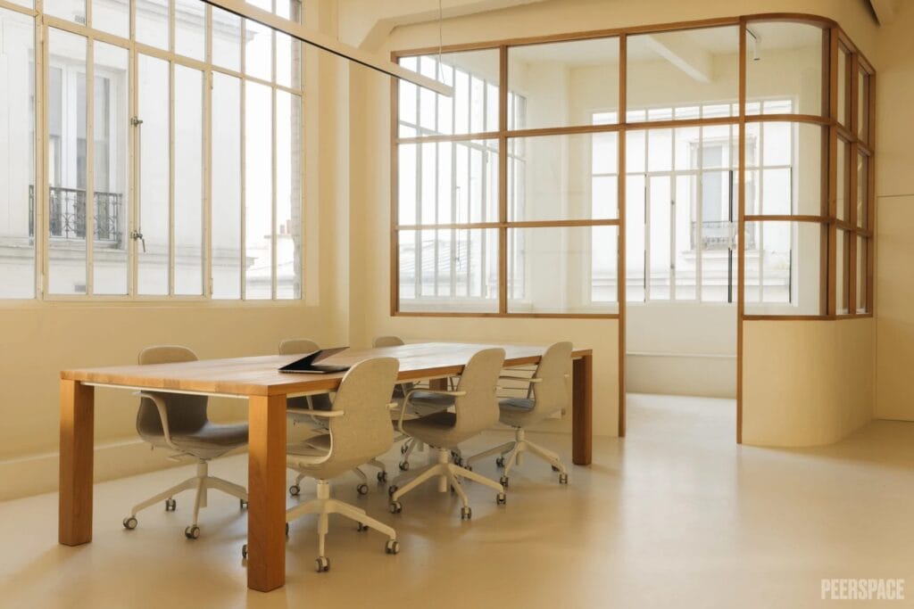 Large windows surround an office space with a small table and separate meeting room