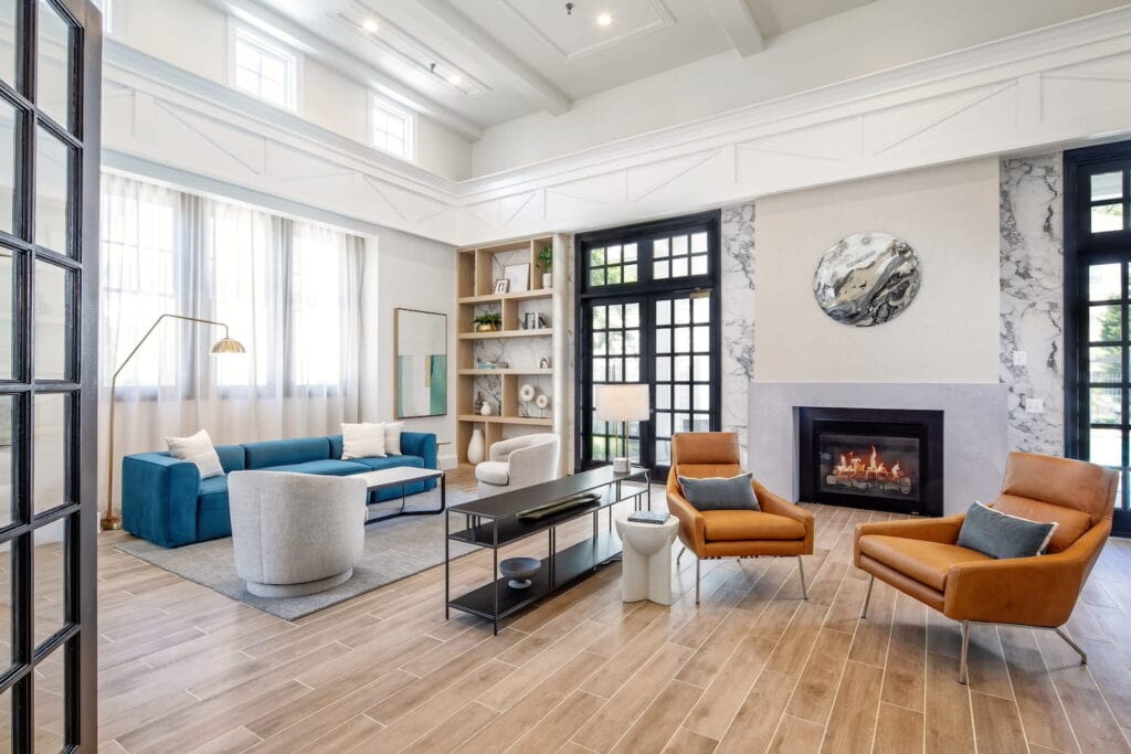 A sunlit lounge with tall ceilings, an aqua couch, and leather chairs