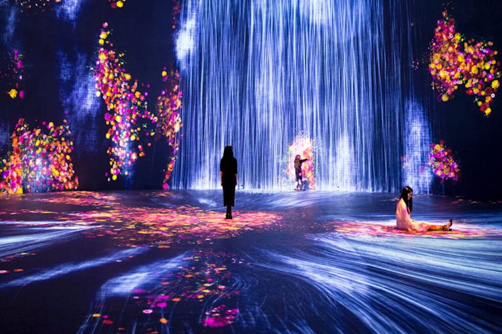 People interact with abstract fluorescent lights projected on walls and flooring