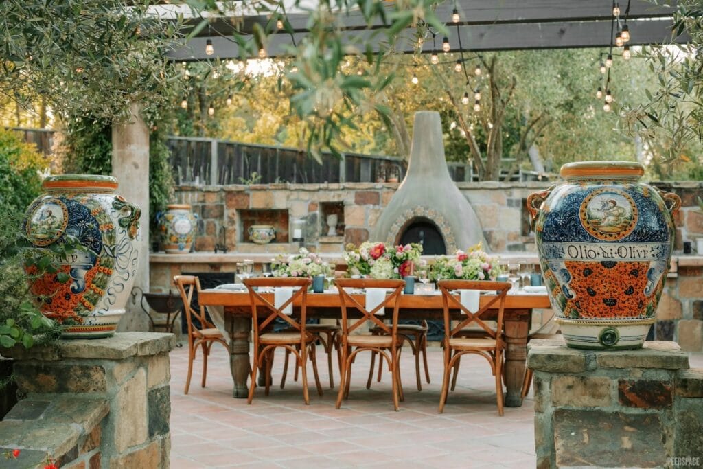 Intimate table set for dinner gathering outdoors in front of large chiminea