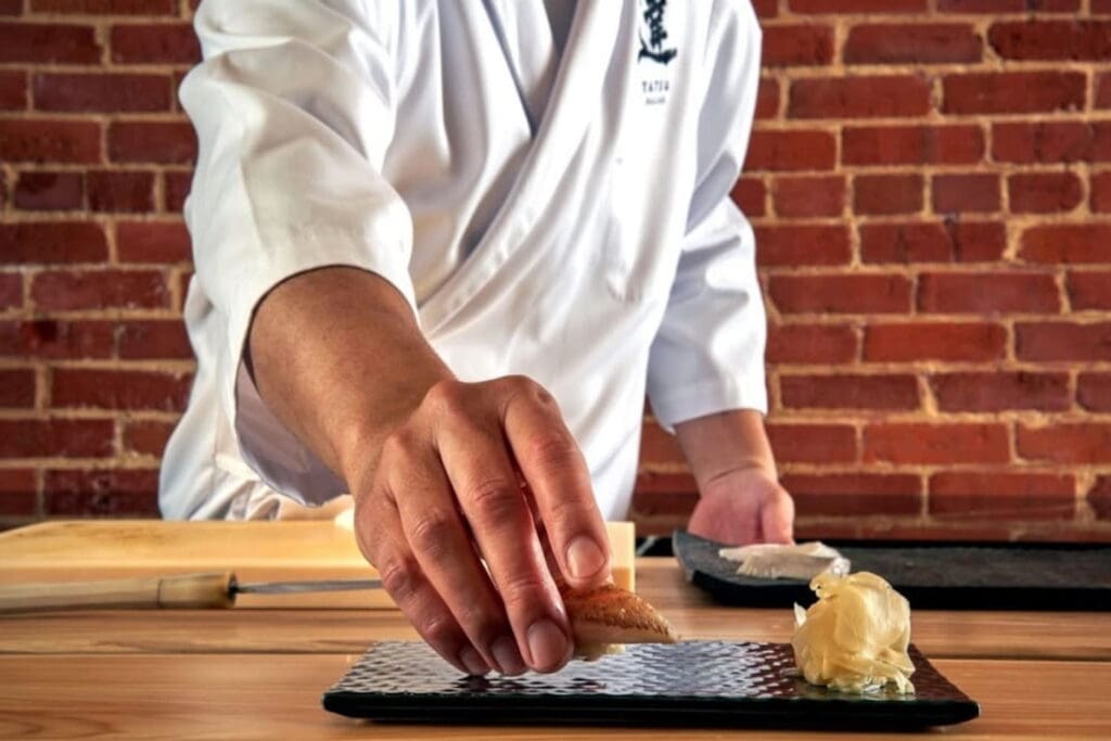 Chef at Tatsu Dallas plates a dish in the foreground