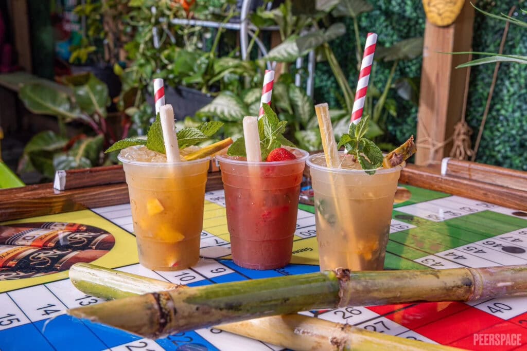 A trio of fruity drinks sits atop a bar in a tropical setting
