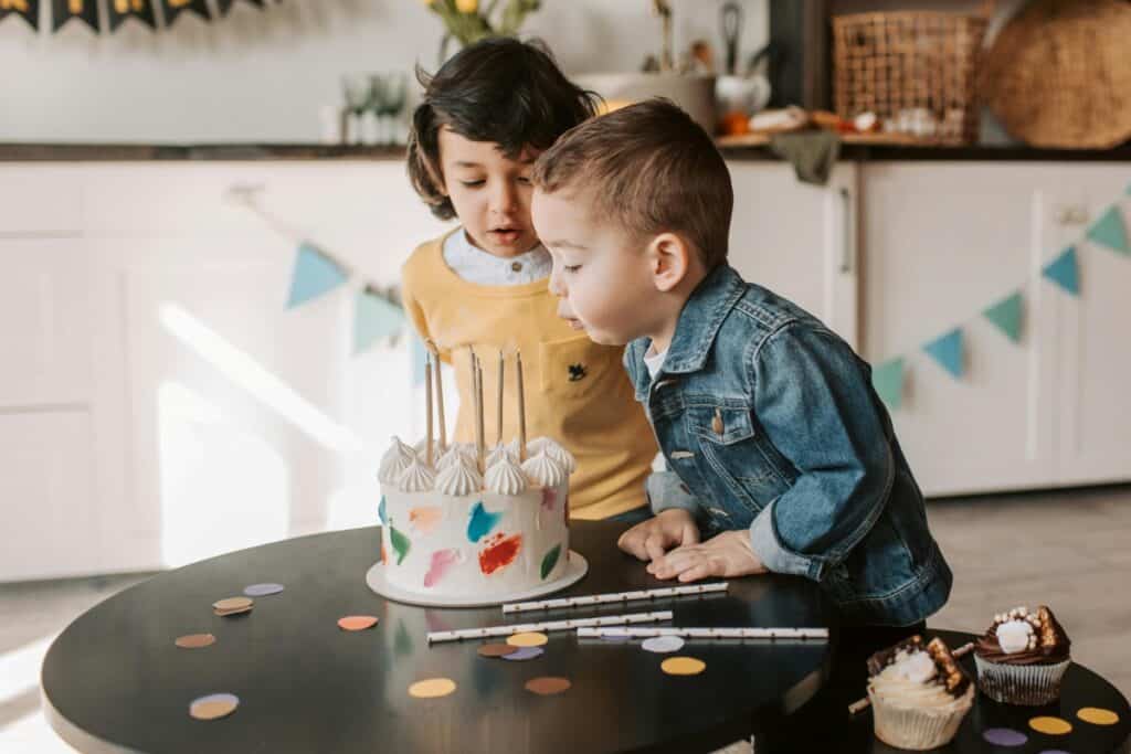 two little boys with a birthday cake and cupcakes