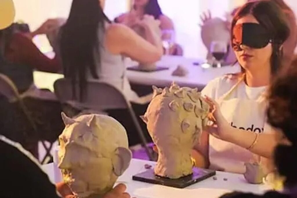 People in blindfolds creating ghoulish creatures out of clay