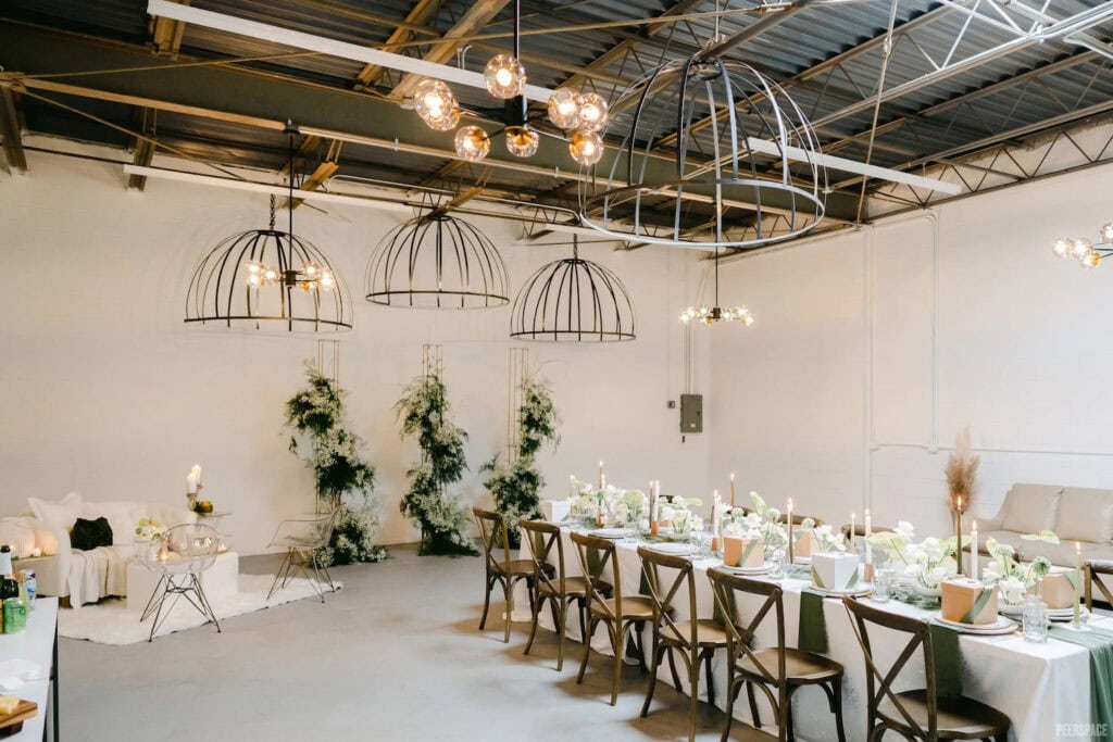 High ceilings punctuate a brightly-lit urban wedding venue decorated with greens and all-white decor