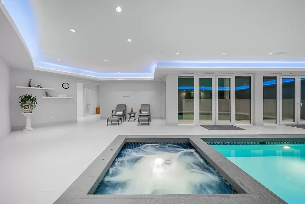 An indoor swimming pool and hot tub in a big, bright space