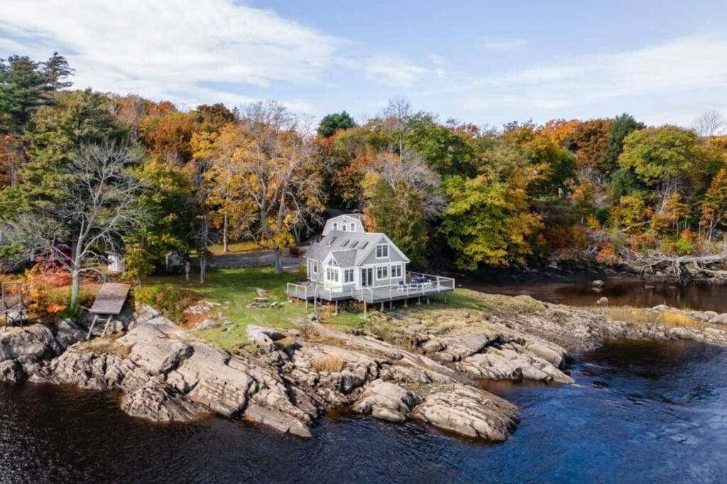 Aerial shot of a waterfront cottage in the fall in New England