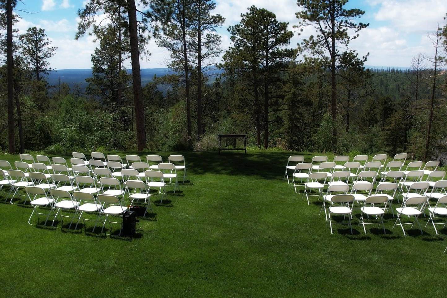Outdoor ceremony setup on green lawn with lake and mountain views