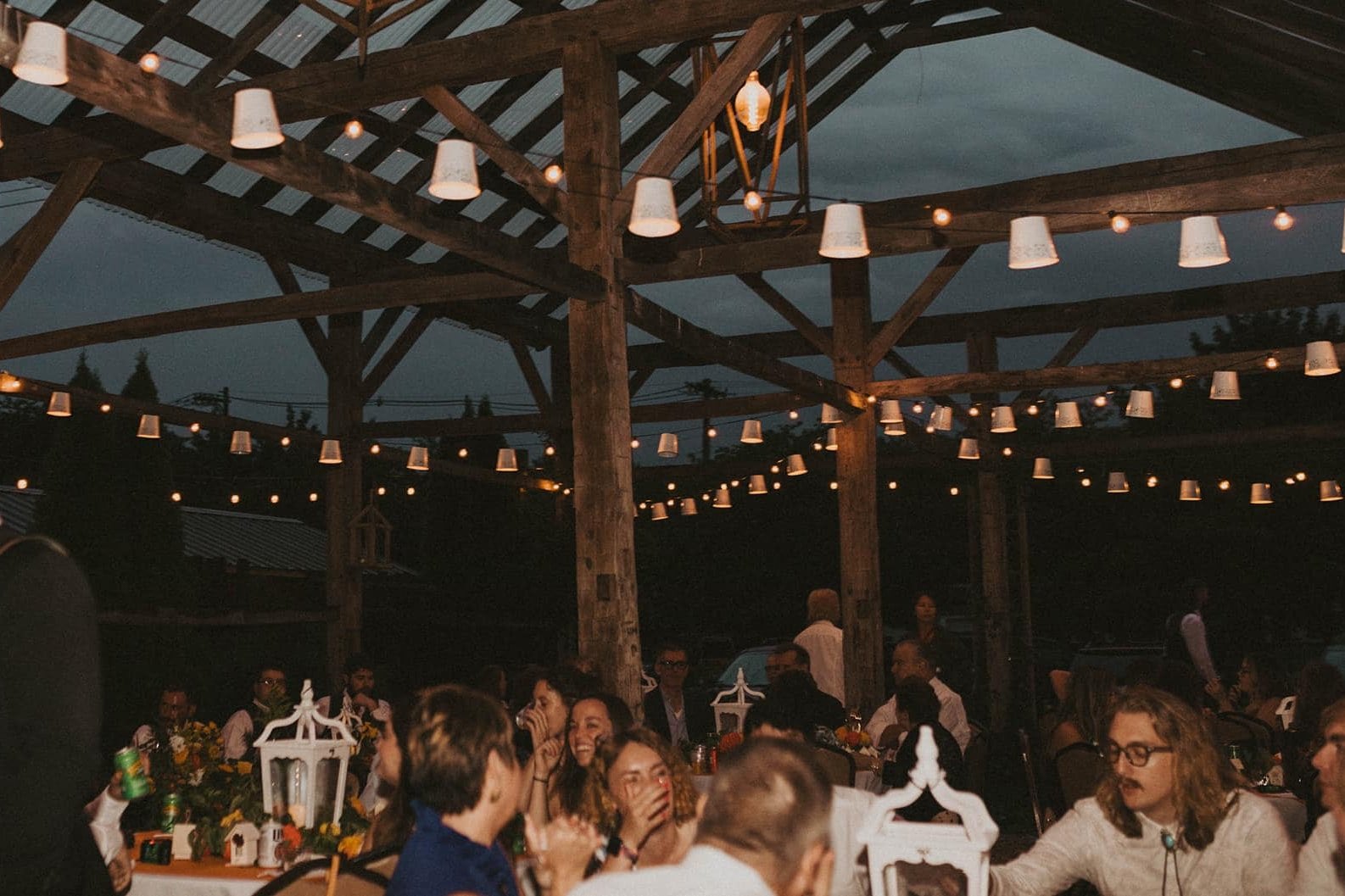 Anchorage wedding reception under wooden pergola with warm lights and evergreens