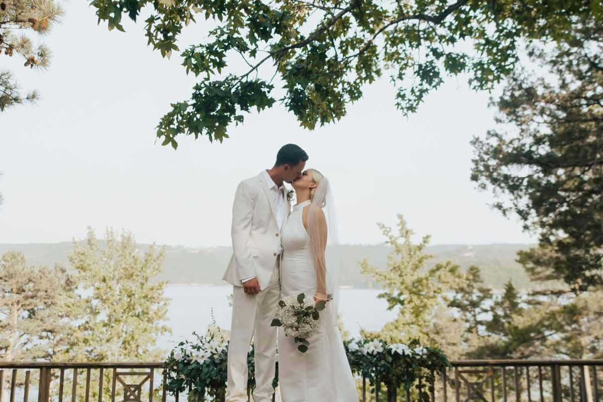 Bride and groom kissing on lakeside deck at Arkansas wedding venue