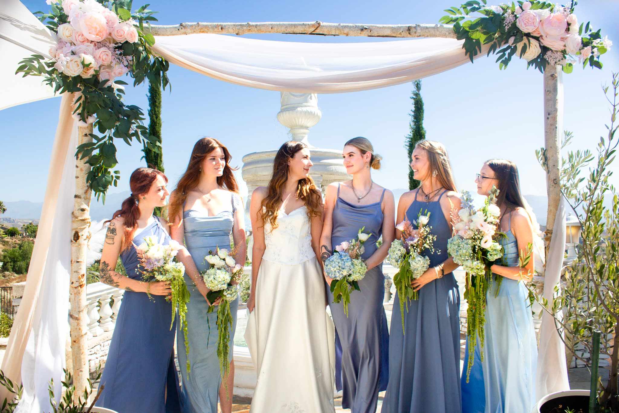 Bridal party beneath floral ceremony arch at upscale Beverly Hills wedding
