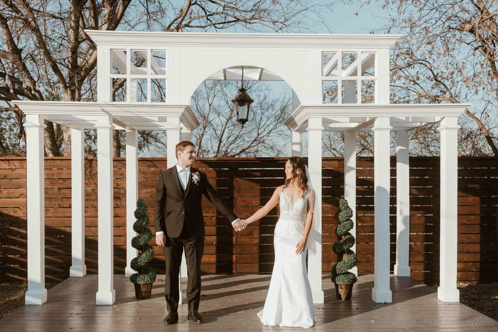 Bride and groom standing under pergola at outdoor Buffalo wedding venue