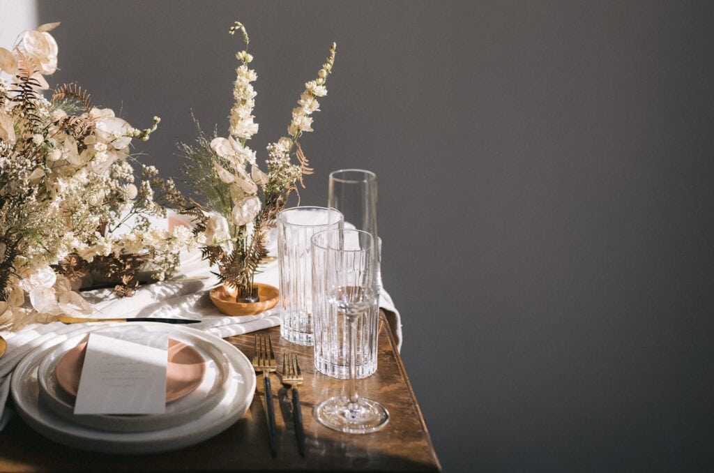 Elegant table setting with florals, drinking glasses, and wood table at Cleveland wedding venue