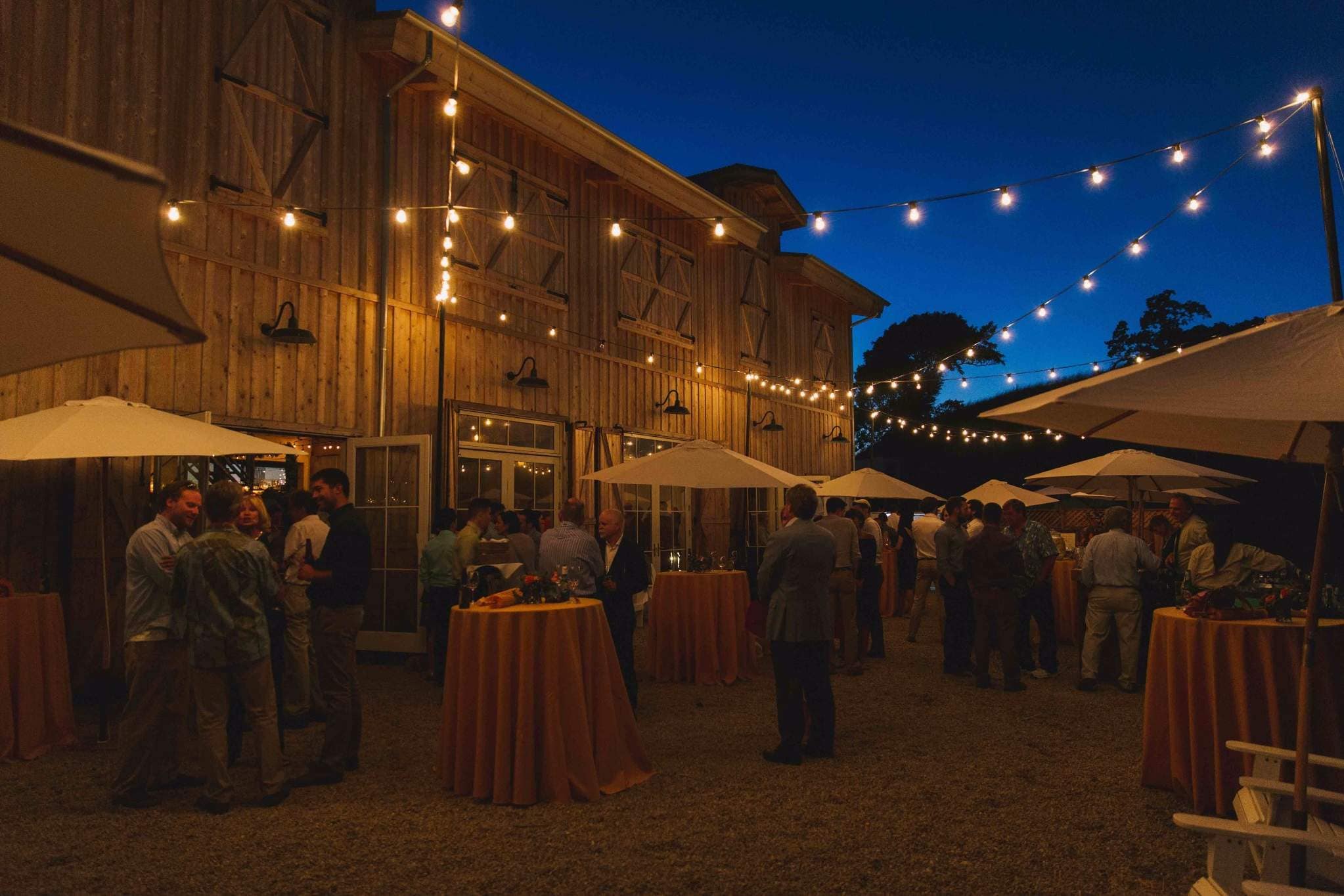 Evening outdoor Fort Wayne wedding reception with string lights and barn