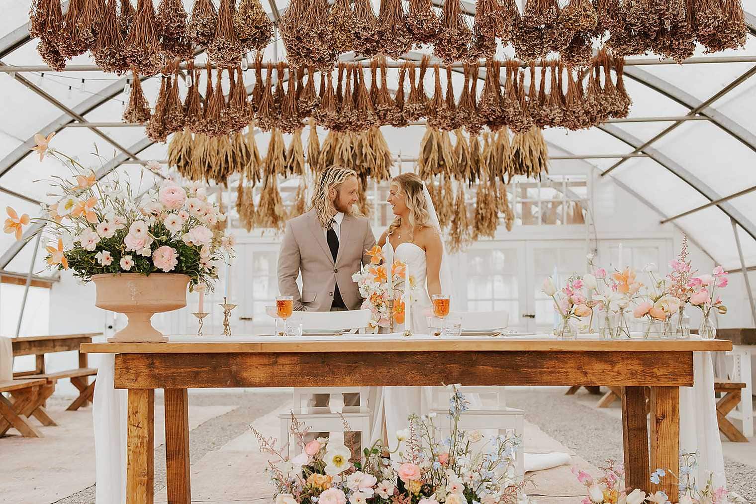 Couple in greenhouse Idaho wedding venue with dried floral canopy
