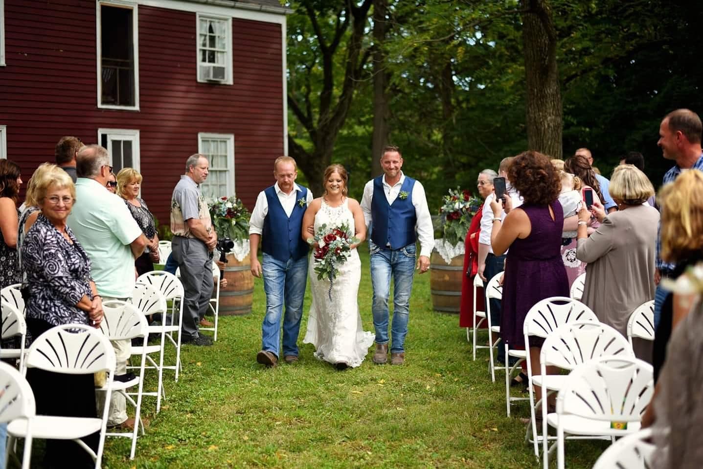 Bride walking down aisle at red barn Iowa wedding venue