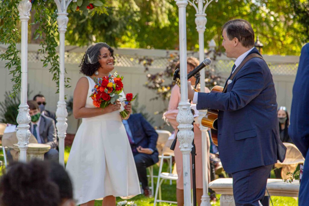 Couple exchanging vows under floral arch at outdoor Kansas wedding ceremony
