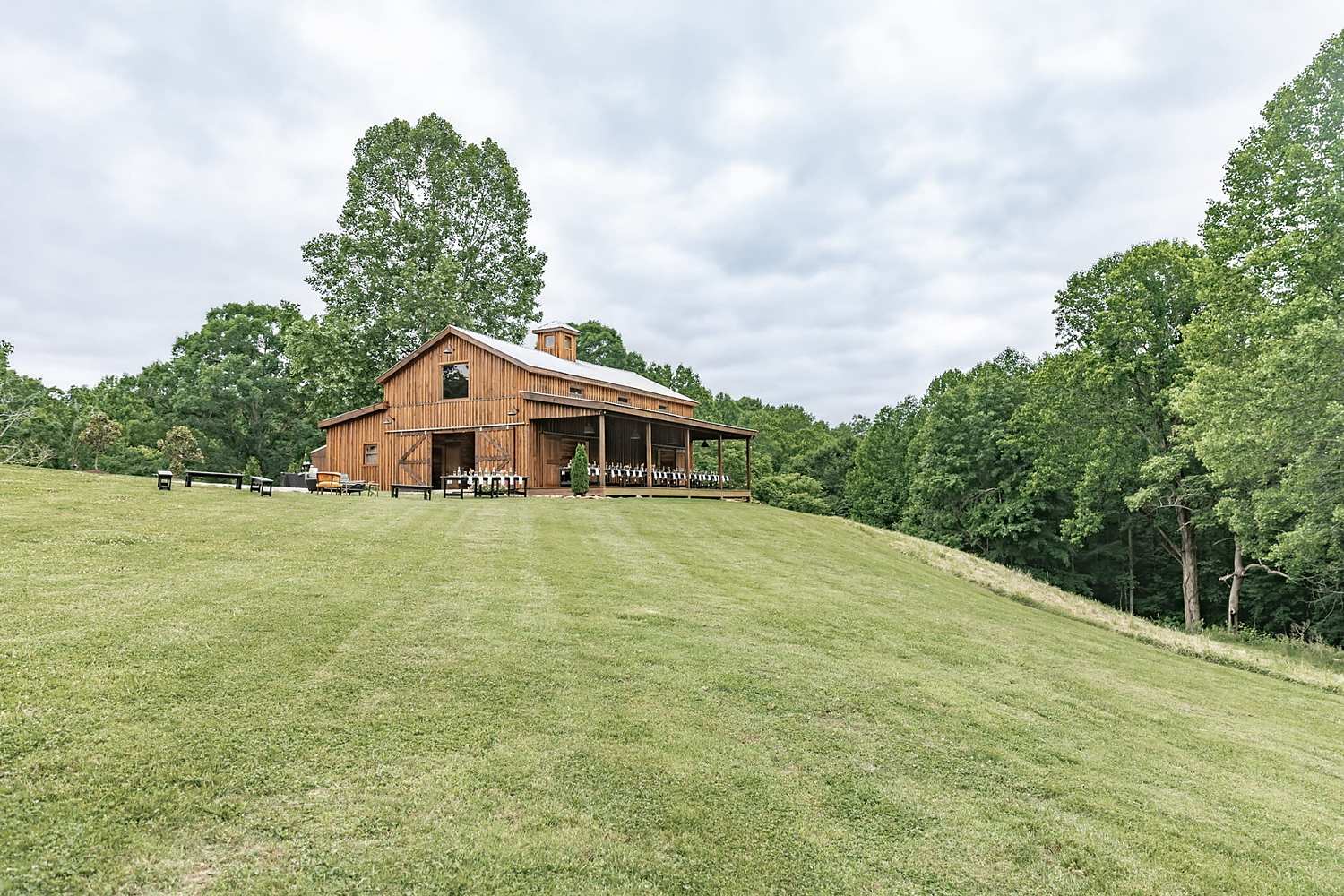 Rustic barn wedding venue on Kentucky hillside with green lawn