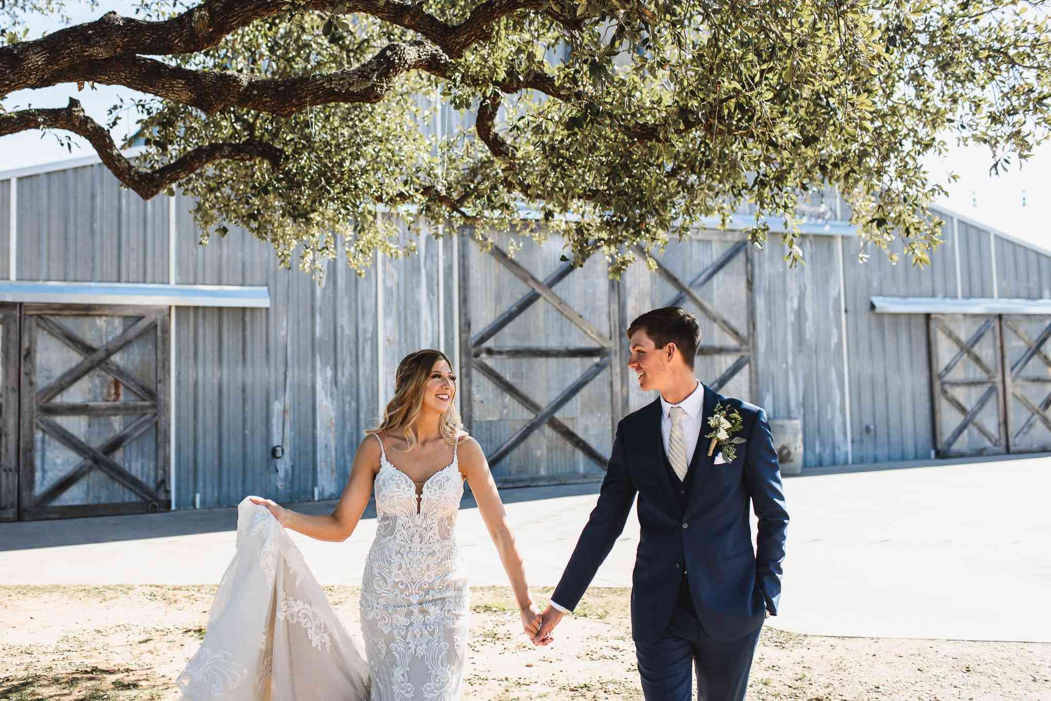 Bride and groom standing before rustic metal barn at Lubbock wedding venue