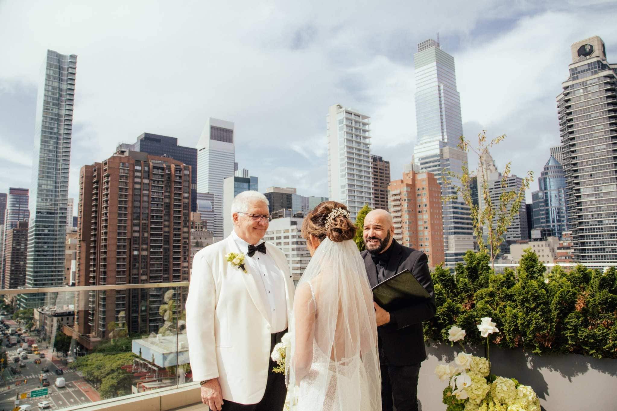 Rooftop wedding ceremony with groom, bride, and officiant overlooking Manhattan
