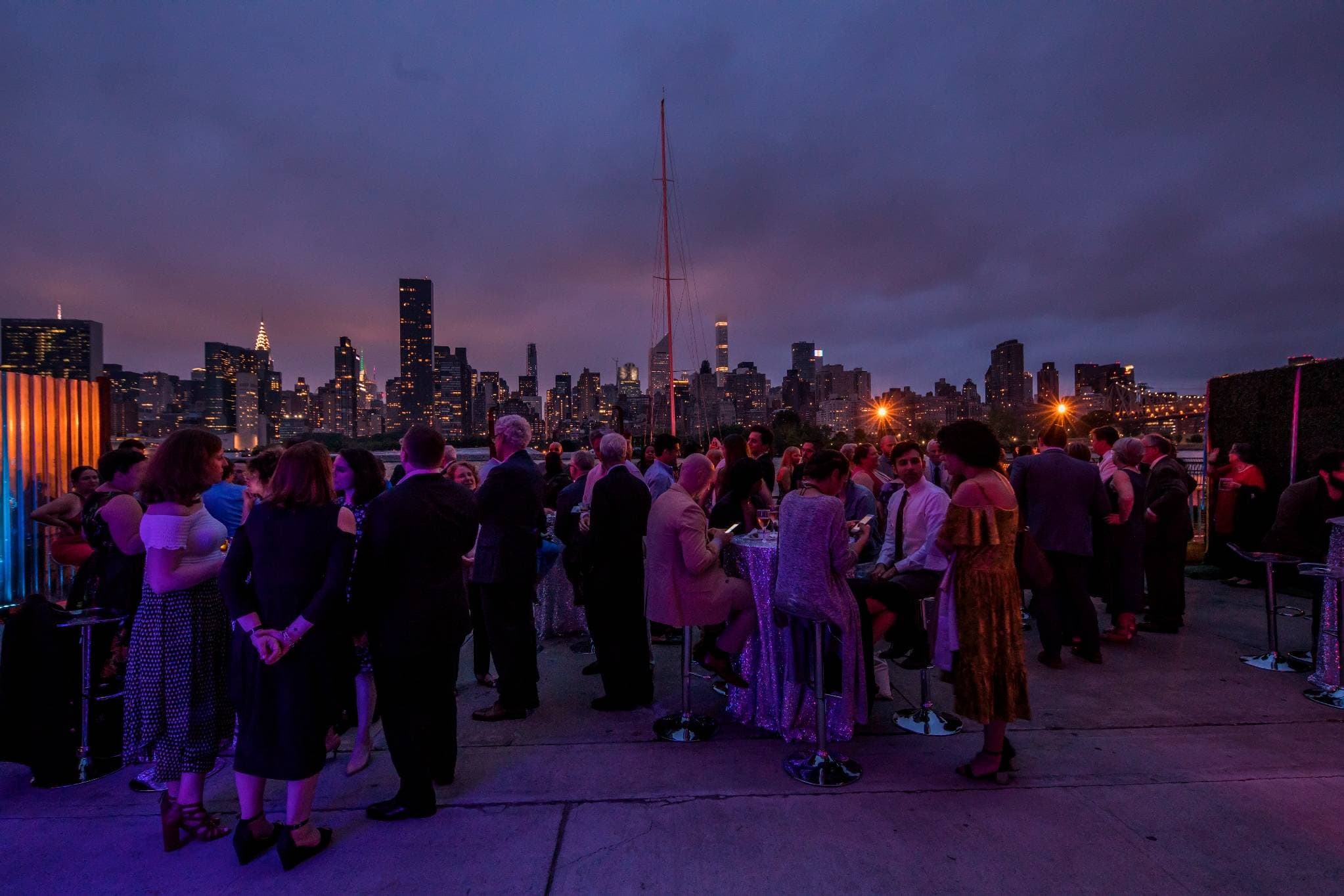Upscale rooftop cocktail celebration at twilight with Manhattan skyline