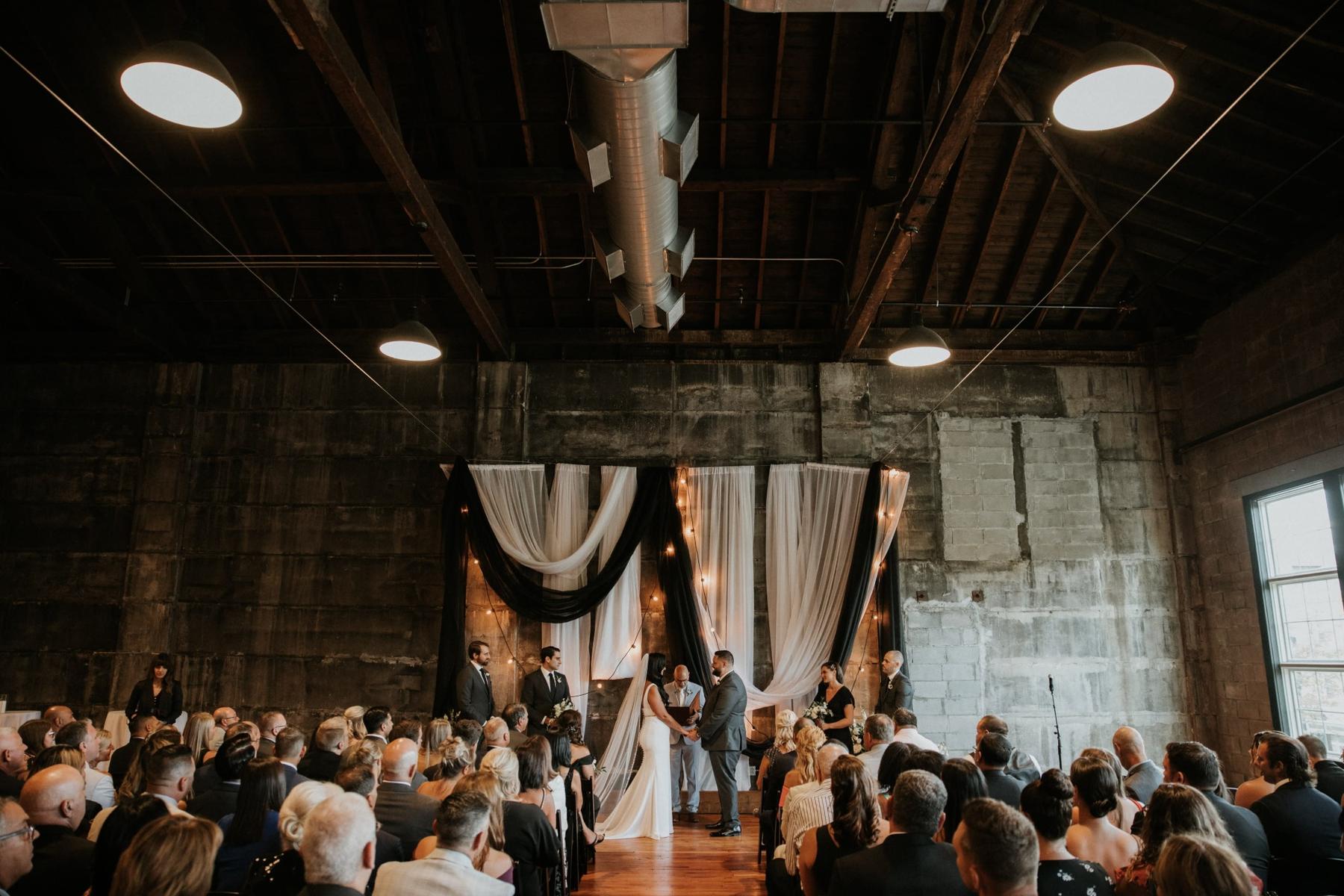 Massachusetts wedding ceremony in industrial-chic venue with draped fabric