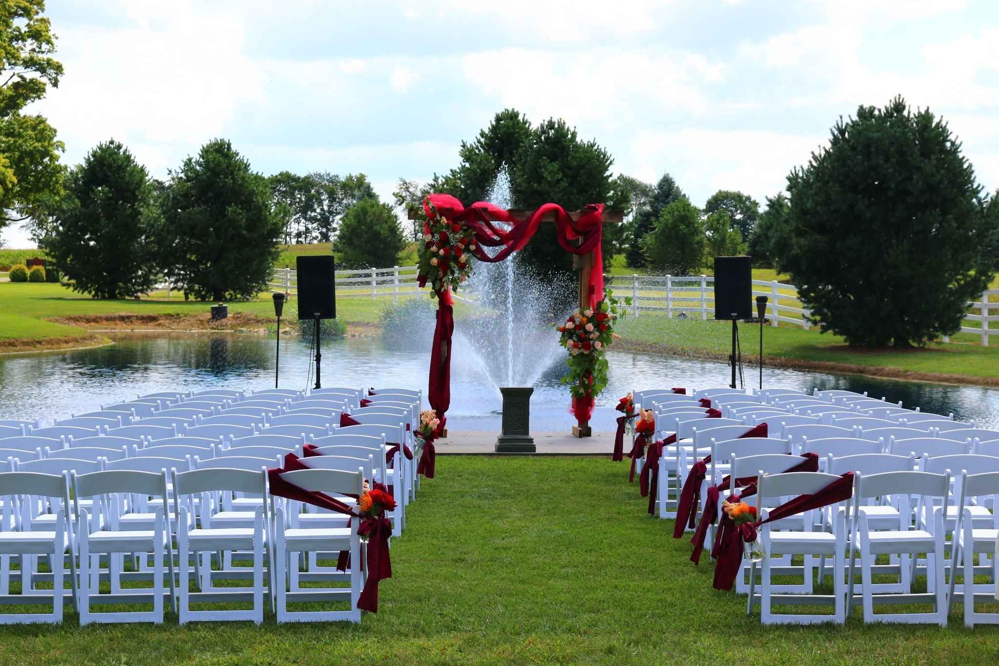 Outdoor Ohio wedding ceremony with arch, chairs, and pond